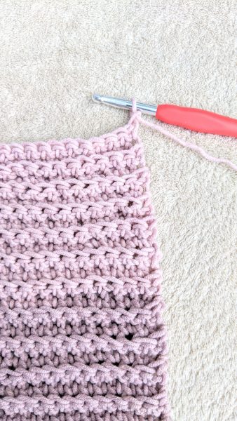 crochet hook with a loop on it in the process of crocheting a scarf