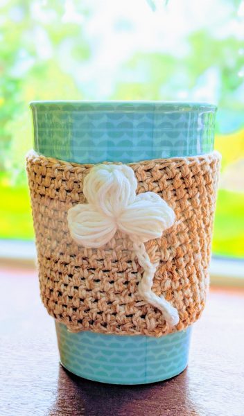 Crochet cup sleeve with white flower and green cup