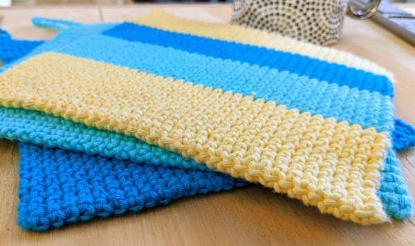 three crochet potholders on the table