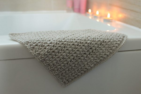 crochet washcloth on top of bath tub, candles in the background