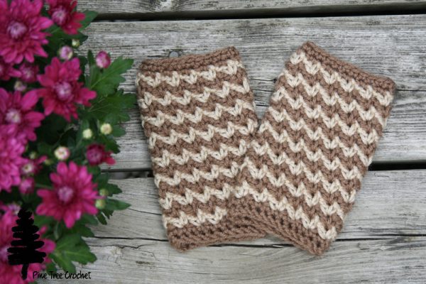 a pair of crochet fingerless gloves in brown and white on wooden background