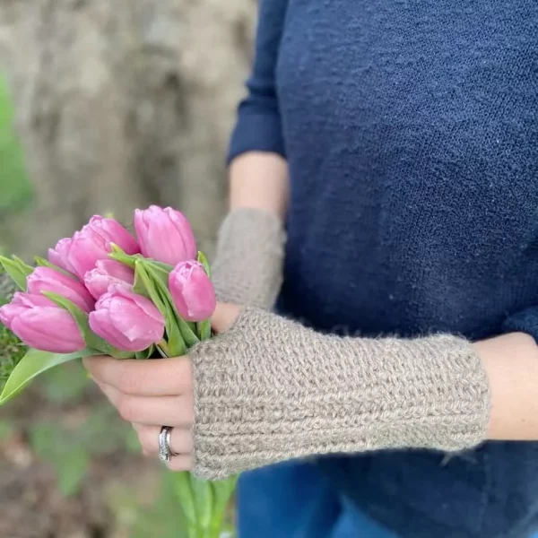 a woman holding pink tulips and wearing beige fingerless gloves