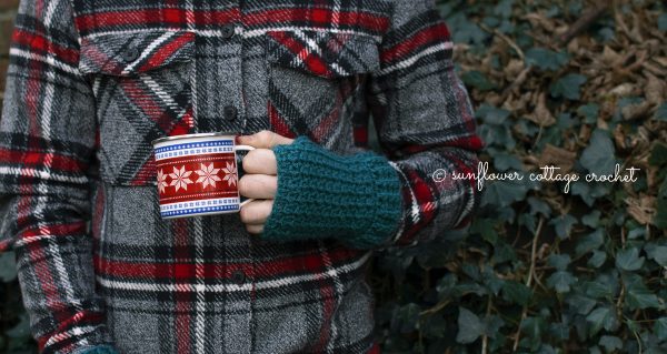 a man holding a cup while wearing teal coloured fingerless gloves in front of green wall 