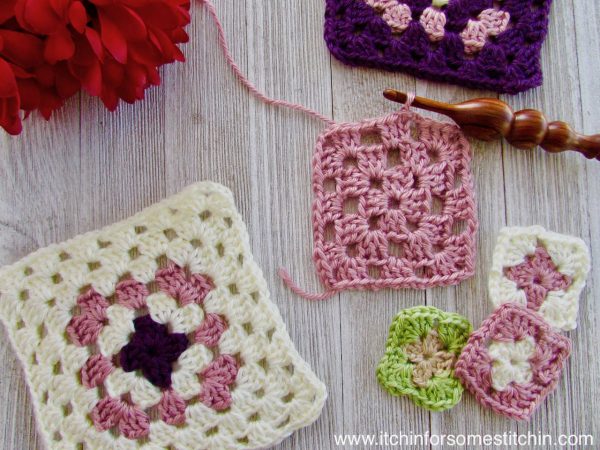 two larger crochet squares in white and pink and three smaller granny squares in green, pink and white