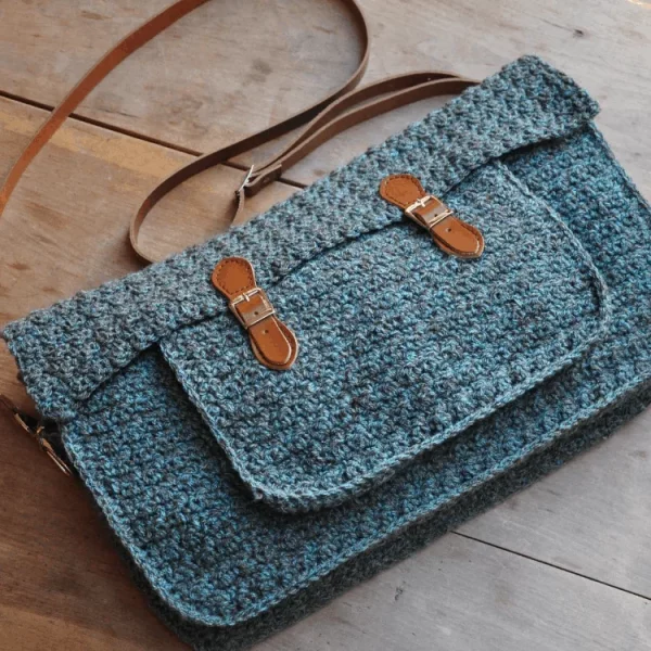 Blue tweed-look crochet purse on a wooden background.