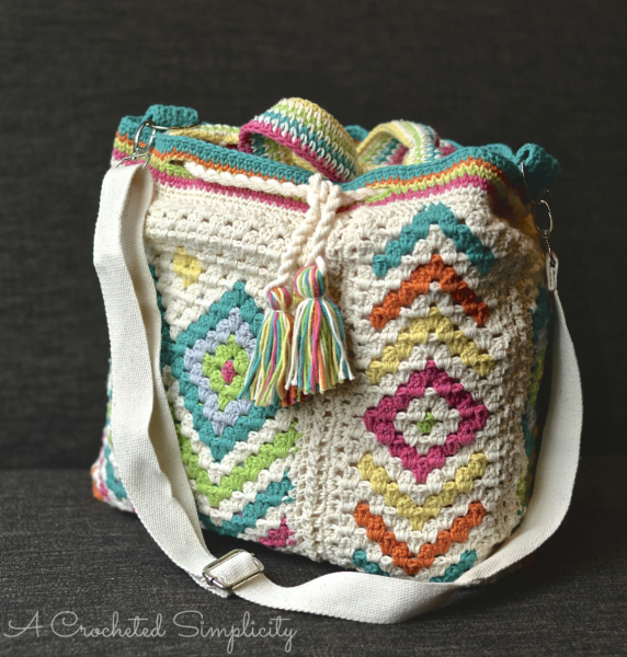 White crochet bag with green, yellow, and red pattern on a black background.