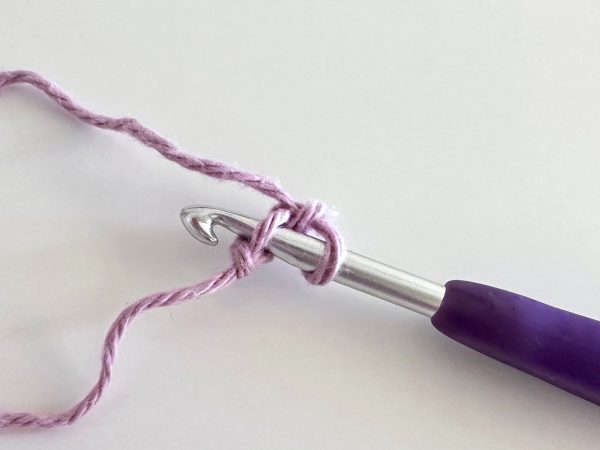 hook inserted into the first stitch, demonstrating the second step of the foundation single crochet stitch.