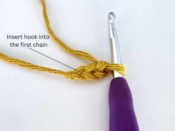 Three chained stitches and a purple hook, illustrating the first step of the foundation double crochet stitch