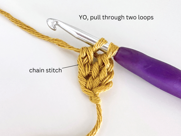 Two loops on a hook, with golden yellow yarn and purple hook, illustrating the seventh step of the foundation double crochet stitch