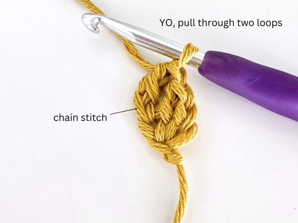 One loop on a hook, with golden yellow yarn and purple hook, illustrating the last step and completion of the second foundation double crochet stitch