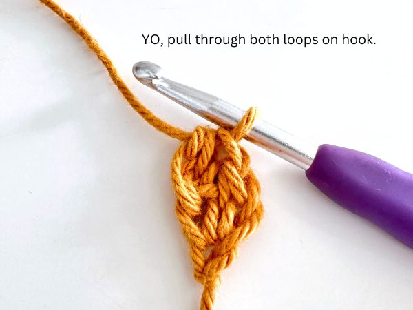 One loop on the hook, illustrating the completion of the second foundation half double crochet stitch.