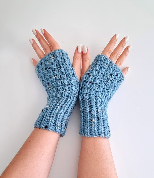 Pair of hands showcasing blue tweed crochet fingerless gloves