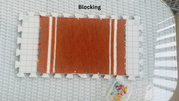 brown crochet placemat on a blocking board with text - blocking