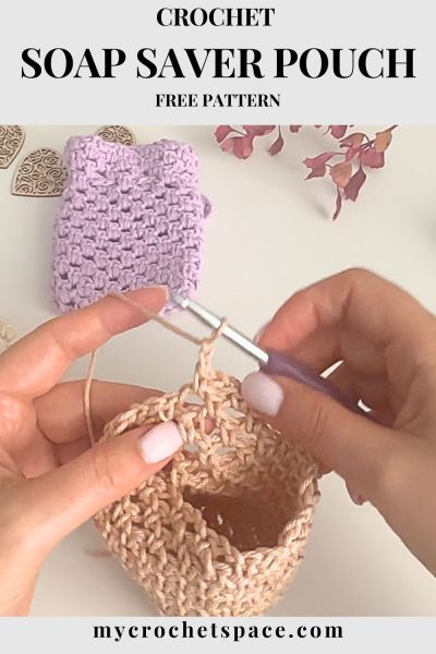 Close-up of hands crocheting a beige soap saver pouch with a crochet hook, with a finished lavender soap saver and decorative hearts in the background.